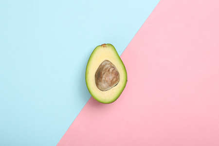 Half of ripe avocado fruit on a blue-pink pastel background. top view