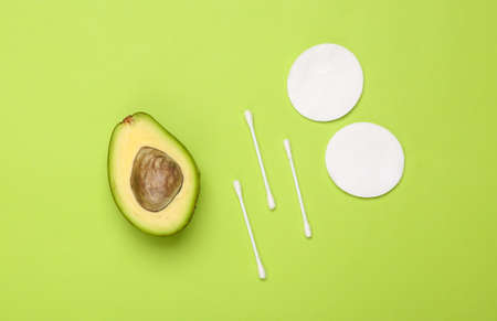 Avocado with cotton pads and sticks on a blue background. Alternative skin care, natural cosmetics