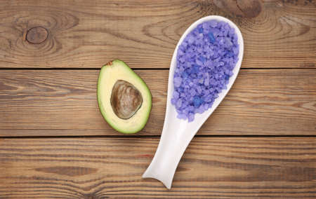 Ripe avocado fruit with a spoon of bath salt on wooden background. natural cosmetic conceptの写真素材