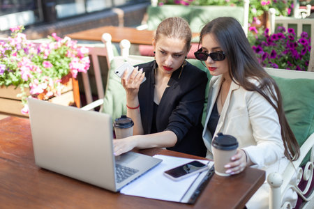 Two business women are studying important information while looking at the laptop screen while...