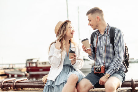 Young loving couple of tourists spend time together on the background of the yacht club