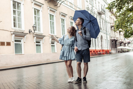 Young couple in love with umbrella stroll through the city in rainy weatherの写真素材