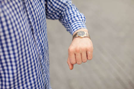 Young man looking at his wristwatch in the cityの写真素材