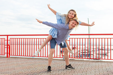 Enjoying every moment together. Young couple in love having fun outdoors while handsome man giving his girlfriend piggy back ride. Romantic, love conceptの写真素材