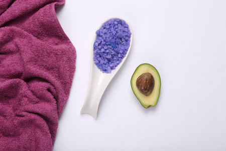 natural cosmetic. spa treatments. Spoon of bath salt and avocado with towel on white background