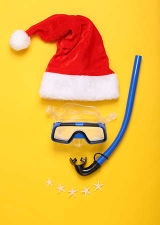 Diving set and santa claus hat on yellow background, Christmas holidays on the beach in warm country concept. top view. flat layの写真素材
