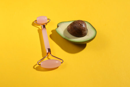 natural cosmetic. Massage roller and half avocado on yellow backgroundの写真素材