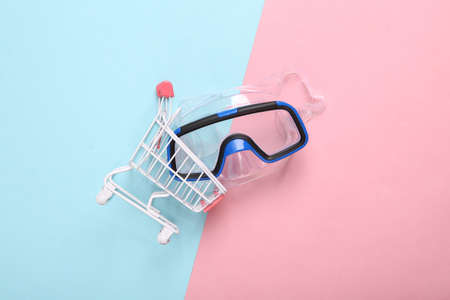 Mini shopping cart with diving mask on blue pink pastel background
