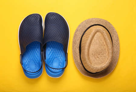 Rubber beach sandals and hat on yellow backgroundの写真素材