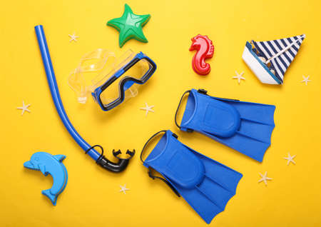 Children's beach accessories. Diving set and sand toys on a yellow background. top view