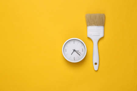 Paintbrush with clock on yellow background. repair time. creative layoutの写真素材