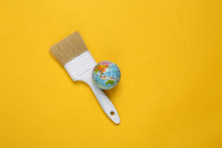 Paintbrush with globe on yellow background. creative layoutの写真素材