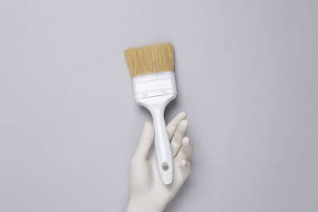 Plastic hand holding paintbrush on gray backgroundの写真素材