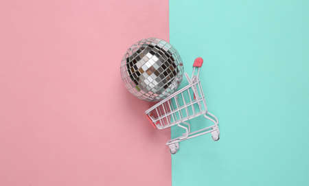 Shopping cart with disco ball on blue-pink pastel background. party concept. creative minimal layoutの写真素材