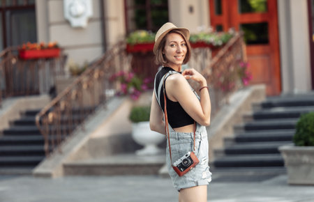 young hipster woman in denim overalls with retro camera in the cityの写真素材