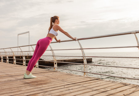 Slim fit woman push up from the railing on the beachの写真素材