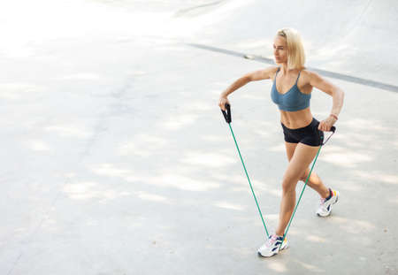 Young athletic woman exercising with a rubber expander outdoors. healthy lifestyleの写真素材