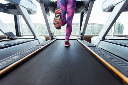 Close-up of female legs running on a treadmill