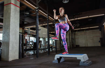 Young fit woman pulls on a stepper in the gym. Aerobics, fitness concept