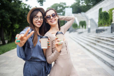 Two beautiful young women having fun together with coffee cup in city.の写真素材