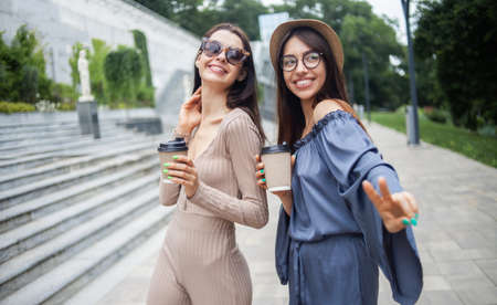 Two beautiful young women having fun together with coffee cup in city.