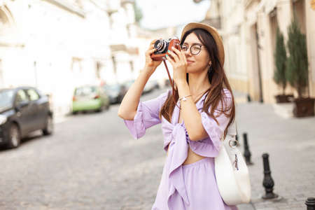Beautiful young woman tourist photographs urban architecture on a European street. travel conceptの写真素材