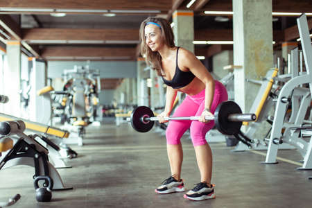 Athletic young woman trains back muscles with a barbell in the gym. healthy lifestyleの写真素材