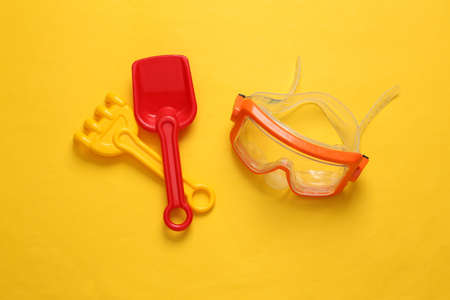 Diving mask, rake and shovel on yellow backgroundの写真素材