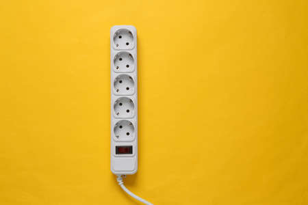 Electrical Extension cord on yellow background. top view. flat lay