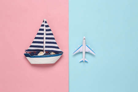 Toy passenger plane and sailboat on pink blue background. Voyage, Travel, summer vacation concept. top viewの写真素材