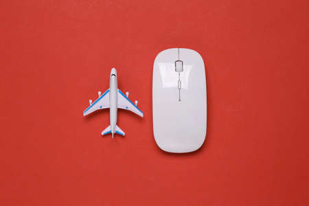Toy passenger plane and pc mouse on red backgroundの写真素材