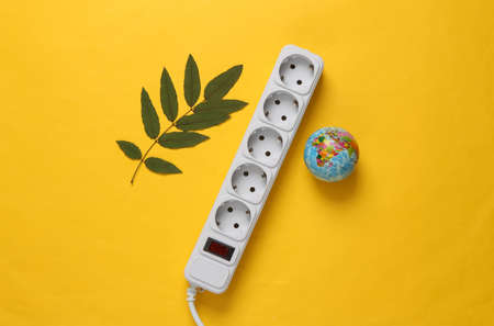 save planet. Electrical Extension cord, globe and green leaves on yellow background. green energy....