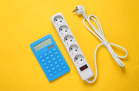 Electrical Extension cord and calculator on yellow background. top view. flat layの写真素材