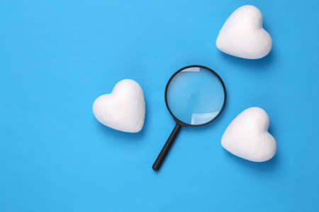 Searching for love concept. Magnifier with hearts on a blue backgroundの写真素材