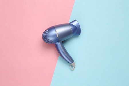 Hair dryer on blue pink background. Minimal beauty layout. top view. flat layの写真素材