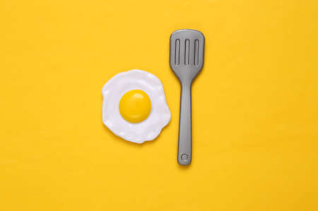 Plastic scrambled eggs and fork on yellow background. top view. minimal food conceptの写真素材