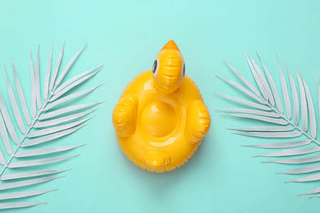 Inflatable duck with white palm leaves on blue background. Minimal summer concept. top view.の写真素材