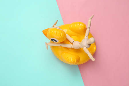 Summer vacation concept. Happy resting puppet on an inflatable duck, pink blue background. top view