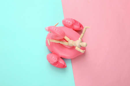 Summer vacation concept. Happy resting puppet on inflatable flamingo, pink blue background