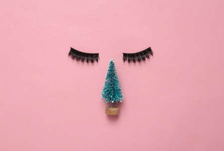 creative layout. False eyelashes and Christmas tree on a pink background. Christmas, new year...