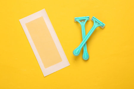 Hair removal razors and depilatory strip on yellow background. body care concept