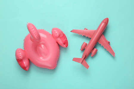 Inflatable pink flamingo and air plane on blue background. Minimal travel concept. top view.の写真素材