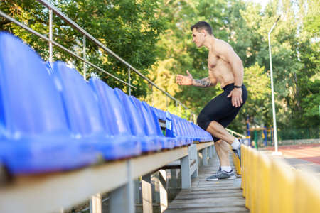 Handsome athletic male runs up the stadium tribune. healthy lifestyleの写真素材