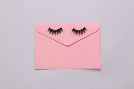 False eyelashes with envelope on gray background