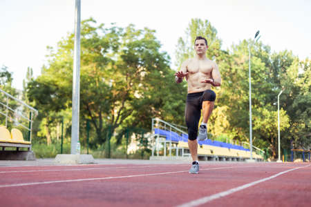Athletic man with a naked torso practicing jumping up, warming up before running to the stadium....