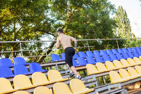Handsome athletic male runs up the stadium tribune. healthy lifestyleの写真素材