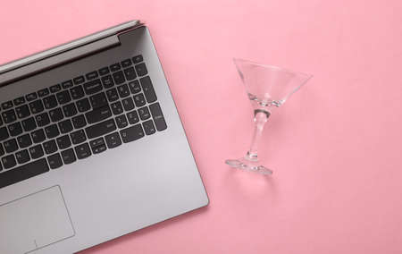 Laptop and empty cocktail glass on pink backgroundの写真素材