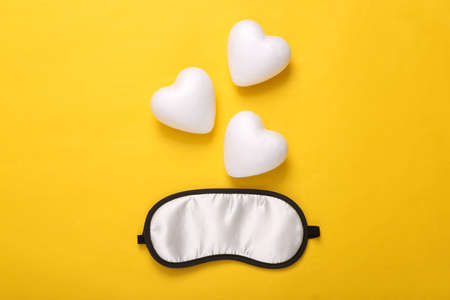 sweet dream concept. Sleeping mask and hearts on yellow background. top view. Minimal styleの写真素材