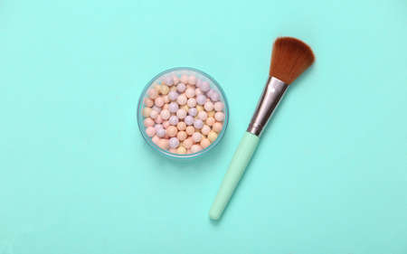 Powder Balls with makeup brush on blue background. cosmetics. top view