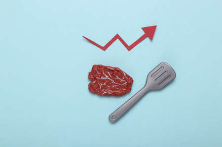 Plastic chop with a growth arrow on a blue background. Increased cholesterol levels